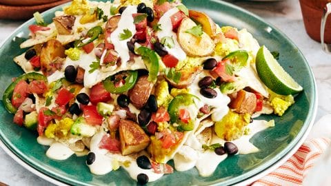 Vegan breakfast nachos with scrambled tofu, black beans, cashew cheese, sour cream, avocado salsa