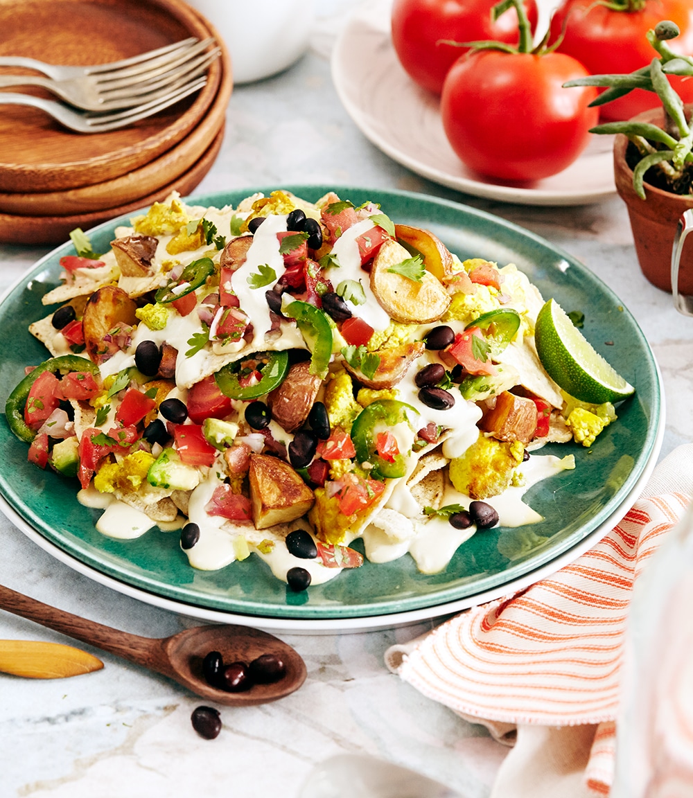 Vegan breakfast nachos with scrambled tofu, black beans, cashew cheese, sour cream, avocado salsa