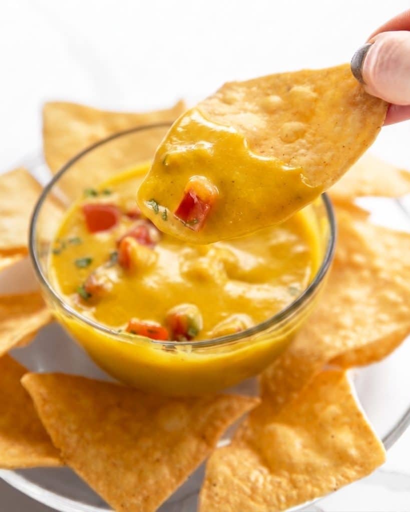 Easy oil-free and nut-free vegan cheese sauce being dipped into with a chip