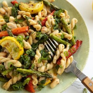 vegan lemon pasta primavera with asparagus, red pepper, yellow squash and kale