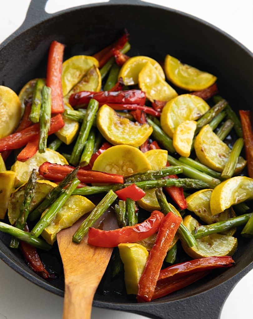 Red pepper, asparagus and summer squash cooking in a cast iron skillet